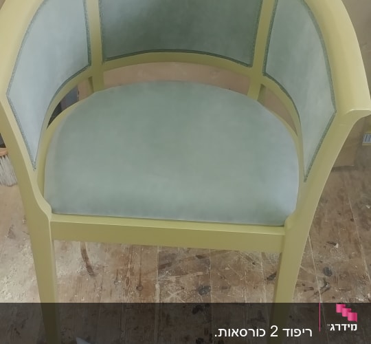 כיסא מרופד עם מסגרת ירוקה על רצפת עץ
